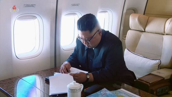 북한 조선중앙TV가 14일 방영한 북미정상회담 기록영화에서 김정은 북한 국무위원장이 싱가포르로 향하는 중국 고위급 전용기 안에서 회담 관련 문건로 보이는 서류를 들여다 보고 있다 [이미지출처=연합뉴스]