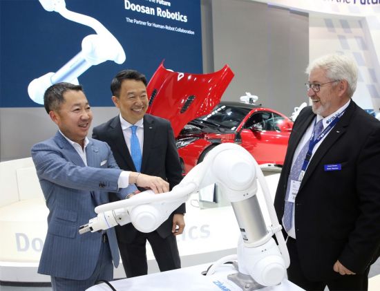 박정원 두산그룹 회장(왼쪽)이 두산로보틱스 부스에서 독일 로봇시장의 한 딜러 업체 대표(오른쪽)와 협동로봇에 대해 이야기를 나누고 있다.