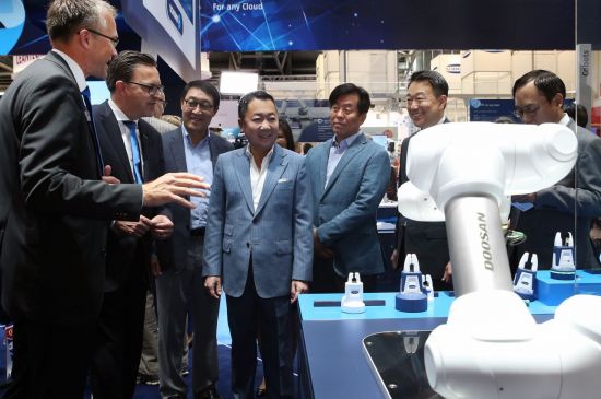 박정원 두산그룹 회장(가운데)이 세계 최대 그리퍼(gripper) 생산 업체인 슝크(Schunk) 부스에 들러 헨리크 슝크 사장(왼쪽에서 두번째)과 함께 앞에 놓인 두산로보틱스 협동로봇에 대해 이야기하고 있다.