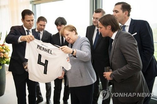 지난 4월 독일 대표팀 유니폼을 전달받는 메르켈 독일 총리. 사진=연합뉴스(EPA)