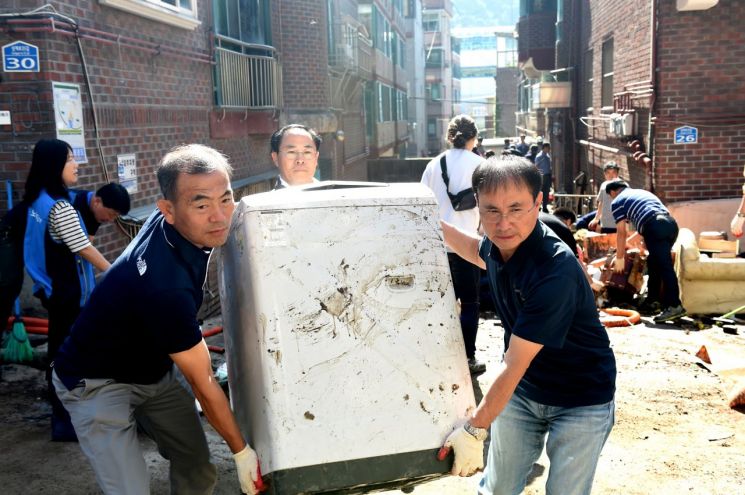 김인철 노원구 부구청장(왼쪽)이 직원들과 함께 수해 복구 작업을 버리고 있다.