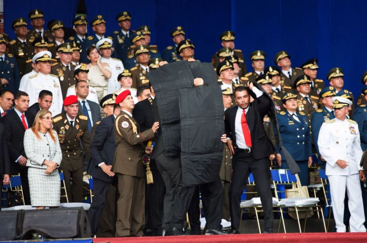 니콜라스 마두로 베네수엘라 대통령이 지난달 4일(현지시간) 수도 카라카스에서 야외 연설 도중 인근 상공에서 폭발물이 터지자 경호원들이 방탄 장비로 마두로 대통령을 둘러싸고 있다.(카라카스 신화=연합뉴스)