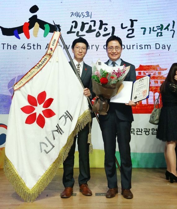27일 열린 45회 관광의 날 기념식에서 신세계면세점 CSR 강현욱 팀장(좌)과 지원담당 임승배 상무가 대통령 표창을 받은 뒤 기념사진을 찍고있다.