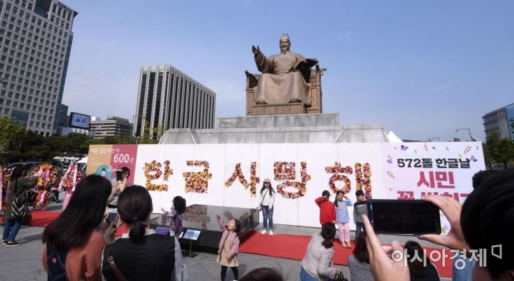 한글날인 9일 서울 종로구 광화문광장에서 열린 한글문화큰잔치 '한글, 세상을 품다'를 찾은 시민들이 세종대왕 동상 앞에 마련된 간이 벽에 '한글 사랑해' 글귀에 맞춰 꽃을 꽂은 뒤 사진을 찍고 있다./김현민 기자 kimhyun81@
