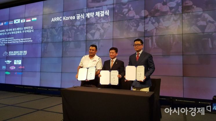론 호그 TWMR 대표와 이동기 대한모터사이클연맹 회장, 조성태 AMK 대표가 내년 ARRC 한국 대회 개최를 위한 계약서에 서명한 뒤 기념촬영하고 있다.