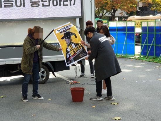 '남성과 함께하는 페미니즘' 측이 '당당위'의 포스터를 태우는 퍼포먼스를 펼치고 있다. (사진=이승진 기자)