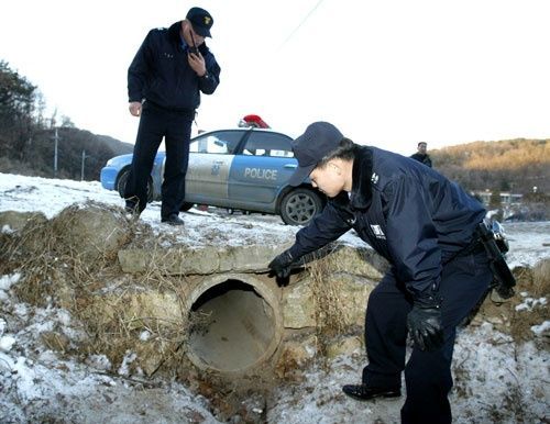 지난 2004년 2월 8일 경찰관들이 실종된 여중생 A 양의 시신이 발견된 경기도 포천시 소흘읍 배수로 현장을 조사하고 있다.사진=연합뉴스