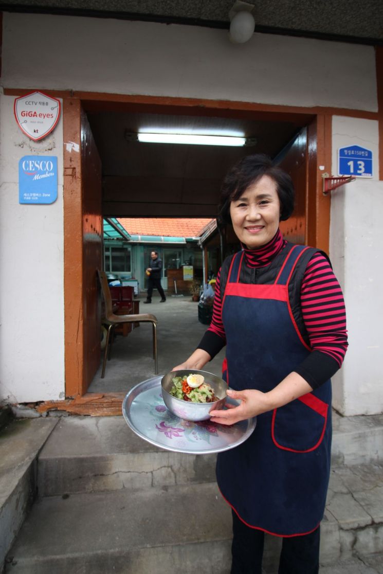 김순오 대표는 어머니로부터 12년 전 가게를 물려받아 '어머니의 막국수'를 만들고 있다. 김순오 대표가 식당 앞에서 비빔막국수를 들어보이고 있는 모습.