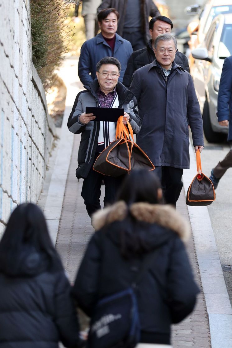 문재인 대통령이 1일 오전 서울 관악구의 한 아파트에서 최영남 나눔공동체 대표와 취약계층 청소년 가정에 도시락 배달 봉사를 하고 있다. 
사진=청와대