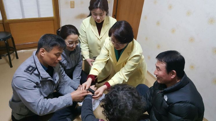 장성군보건소와 장성경찰서 관계자가 치매어르신의 배회감지기 착용을 도와드리는 모습. 사진=장성군