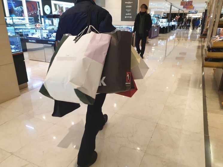 19일 오후 서울 중구의 한 백화점에서 지하철퀵 배달원인 김영춘(67ㆍ가명)씨가 물건을 배달하기 위해 양손 가득 쇼핑백을 들고 이동하고 있다.