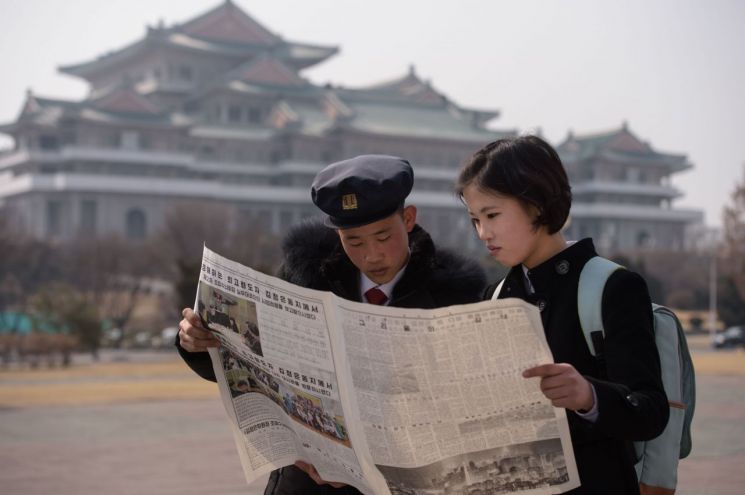 북한 학생들이 27일(현지시간) 평양 거리에서 도널드 트럼프 미국 대통령과 2차 북미정상회담을 앞둔 김정은 북한 국무위원장의 베트남 하노이 도착 소식을 전하는 노동신문을 펼쳐든 채 읽고 있다. <사진=AFP연합>