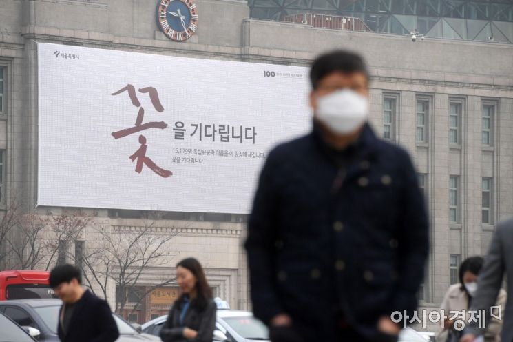 수도권에 엿새 연속 미세먼지 비상저감조치가 발령된 6일 마스크를 쓴 시민들이 서울도서관 외벽에 걸린 '꽃을 기다립니다' 현수막을 지나고 있다. /문호남 기자 munonam@