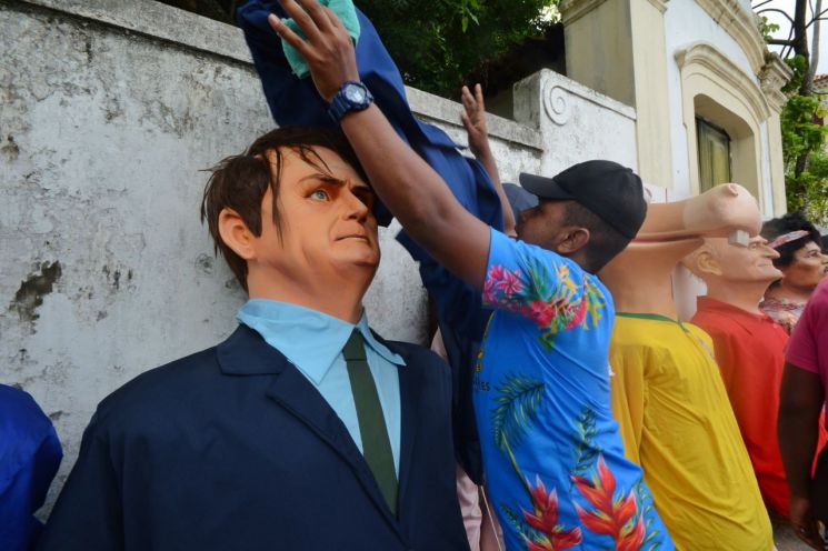 카니발 축제기간인 4일(현지시간) 브라질 올린다에서 한 남성이 자이르 보우소나루 대통령의 모습을 한 퍼레이드 인형을 천으로 덮고 있다. [이미지출처=EPA연합뉴스]