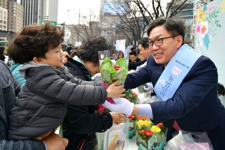 이대훈 NH농협은행장(오른쪽)이 14일 서울 광화문 일대에서 한 어린이에게 화분을 건네고 있다. 사진=농협은행 제공