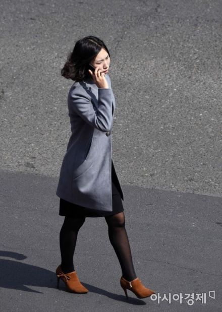 북한 평양에서 휴대전화로 통화하며 길을 걷는 여성.