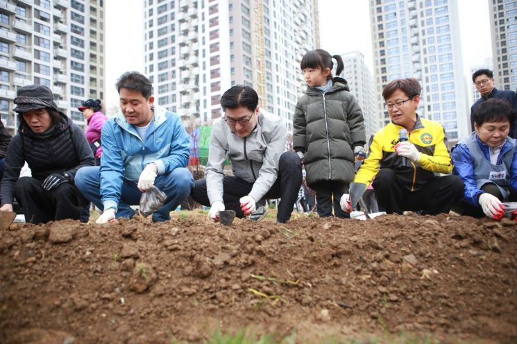 이정훈 강동구청장과 주민들이 명일근린공원 공동체텃밭에서 씨감자를 심고 있다.