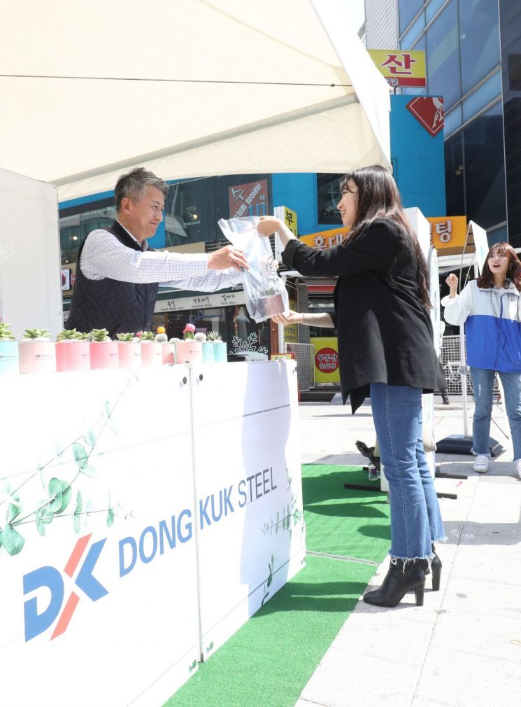 장세욱 동국제강 부회장이 철의 친환경성을 홍보하기 위한 '그린 캠페인' 일환으로 임직원들과 15일 서울 마포에서 한 시민에게 철로 만든 미니 화분을 나눠주고 있다.
