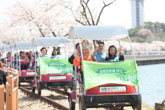 JW그룹 임직원들이 17일 경기도 의왕레일파크에서 우면종합사회복지관 장애·독거노인들과 짝을 이뤄 레일바이크를 타고 있다.