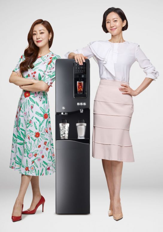 배우 염정아(오른쪽)와 오나라가 청호나이스 이과수 커피얼음정수기 '휘카페550' 제품 옆에서 포즈를 취하고 있다.