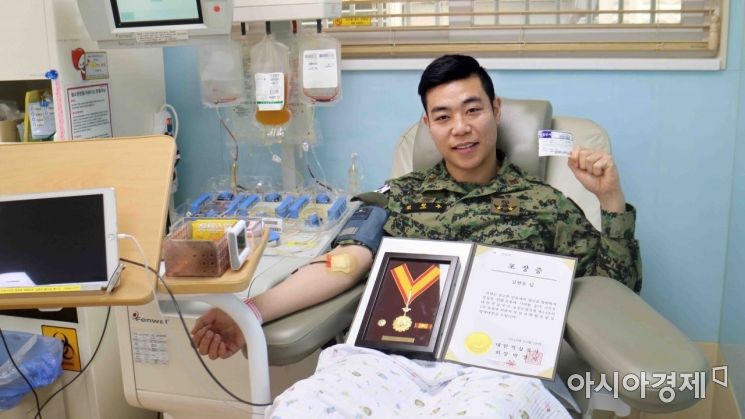 육군 특수전학교 김현우 상사가 헌혈 '명예대장' 포장증을 들고 헌혈을 하고 있다. (사진=대한민국 육군)