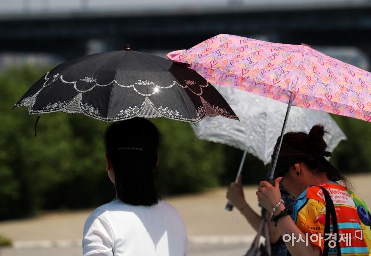 중부와 경북에 폭염주의보가 내려진 25일 서울 반포한강공원에서 시민들이 양산을 쓰고 있다. /문호남 기자 munonam@
