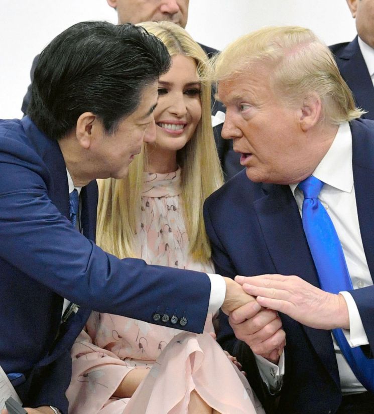 아베 신조(安倍晋三) 일본 총리(왼쪽)과 도널드 트럼프 미국 대통령(오른쪽)이 29일 일본 오사카에서 열린 주요 20개국(G20) 정상회의의 특별 세션에서 트럼프 대통령의 딸 이방카를 사이에 두고 서로 손을 잡으며 대화를 나누고 있다. [이미지출처=연합뉴스]