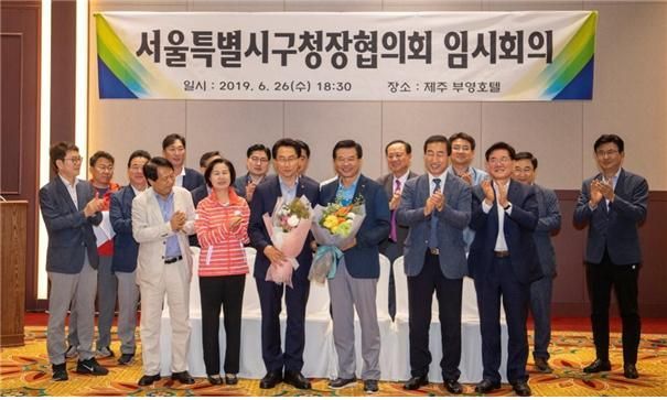 성장현 회장이 지난 6월26일 제주 부영호텔에서 열린 서울시구청장협의회에서 차기 회장으로 추대된 김영종 종로구청장과 함께 꽃다발을 받았다.