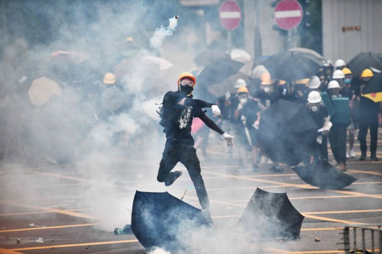 지난 27일 홍콩 위안랑 지역에서 '백색테러' 규탄 시위가 벌어진 가운데 한 시위 참가자가 경찰이 쏜 최루탄을 되던지고 있다. 홍콩 시민 수만 명은 이날 경찰의 집회 금지 통고에도 도로 점거 행진을 강행했다. 이에 경찰은 최루탄 등을 사용해 시위대 강제 해산에 나서면서 부상자도 발생했다. (사진=연합뉴스)