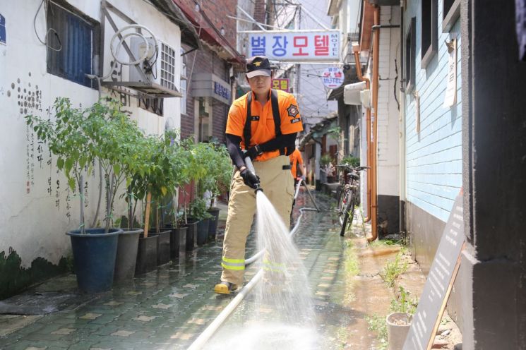 더위를 식히기 위해 한 서울소방재난본부 관계자가 골목길에 물을 뿌리고 있다. (제공=서울시)