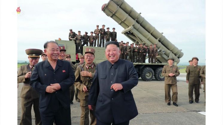 조선중앙TV가 지난 25일 오후 공개한 사진에서 김정은 국무위원장이 방사포를 뒤로 하고 활짝 웃는 모습. 김 위원장 뒤로 최근 북한 신무기 개발의 핵심으로 관측되는 전일호 군 상장이 따라오고 있다.