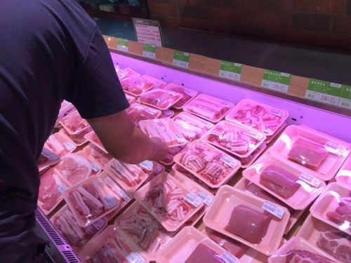 8일(현지시간) 베이징 시내 한 슈퍼마켓에서 고객이 삼겹살 한팩을 집어들고 있다. 중국의 돼지고기 가격은 수급 불균형으로  7월 이후 두 배로 뛴 상황이다.