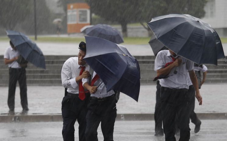 제13호 태풍 '링링'이 상륙한 7일 북한 평양에서 행인들이 우산에 의지해 바람과 비를 피하고 있다. <사진=AP연합>