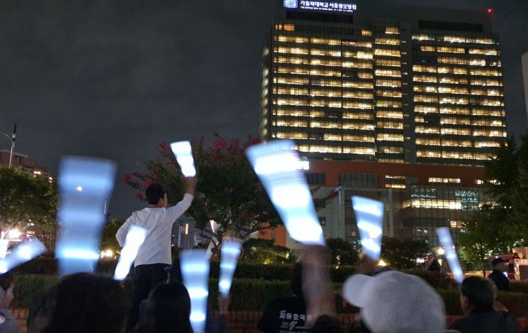 17일 오후 8시 박근혜 전 대통령 지지자들이 서울 서초구 서울성모병원을 향해 '쾌유를 빕니다' 문구가 적힌 형광봉을 흔들고 있다. 박 전 대통령은 이날 오전 왼쪽 어깨 수술을 받고 병원 21층에 입원했다.
