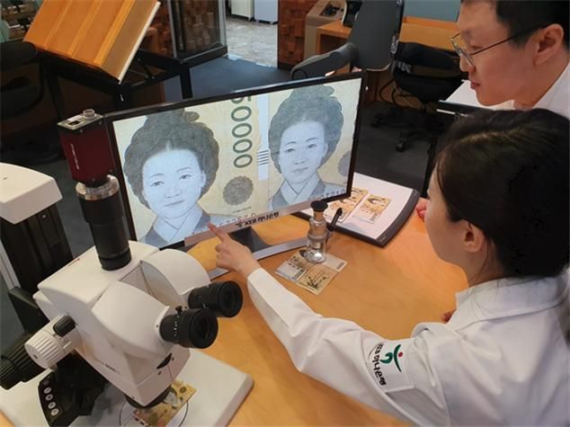 KEB하나은행 위변조대응센터 직원들이 진폐와 위폐를 정밀 감정하고 있다.