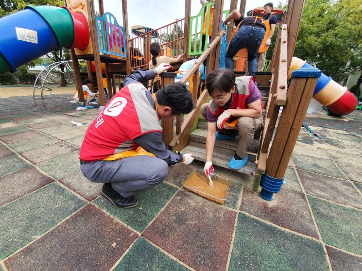 롯데건설 디자인연구소 샤롯데 봉사단이 어린이놀이터를 보수하고 있다.