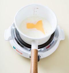 2. 냄비에 우유를 붓고 마늘가루, 파르메산 치즈가루를 넣어 잘 섞은 다음 슬라이스 치즈를 넣는다.