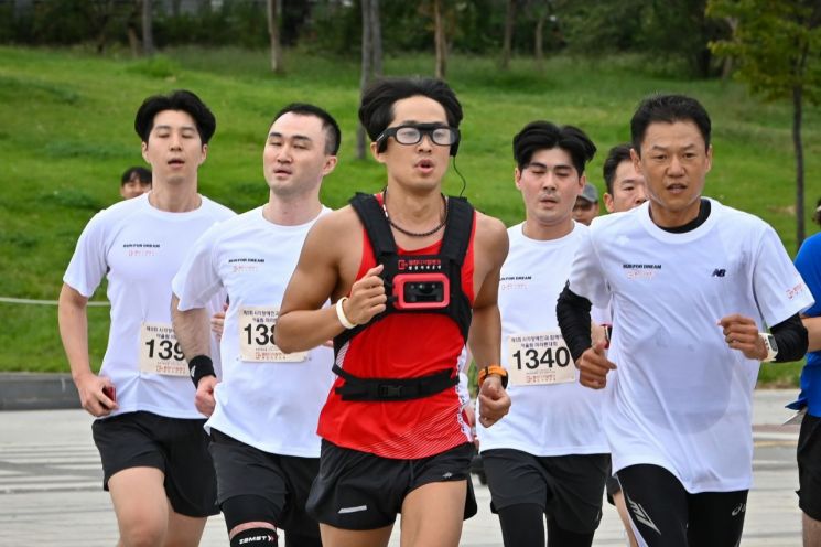 지난 9월21일 서울 여의도에서 열린 한 마라톤 대회에 참가한 시각장애인 마라토너 한동호씨(가운데)가 '웰컴 드림 글래스'를 착용한 채 달리고 있다. 사진제공=웰컴저축은행
