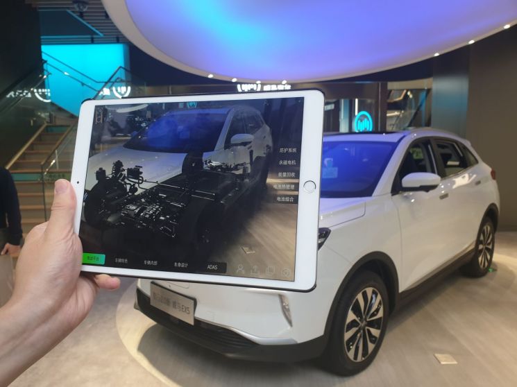 중국 상해 난징시루에 위치한 중국 보급형 전기차 브랜드 웨이마의 전시장에서 전시장 직원이 증강현실 태블릿PC를 활용해 차량 내부를 설명하고 있다./사진=우수연 기자