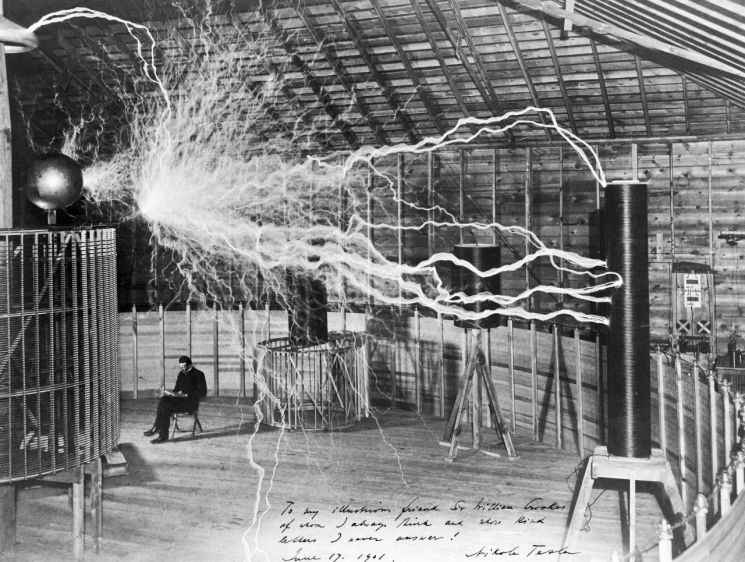 1900년 콜로라도 스프링스 연구소에서 수백볼트의 전류가 흐르는 곳에서 책을 읽고 있는 테슬라의 모습. [사진=위키피디아]