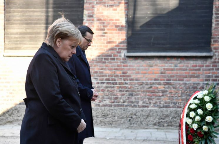 앙겔라 메르켈 독일 총리(왼쪽)가 마테우시 모라비에츠키 폴란드 총리(오른쪽)과 함께 6일(현지시간) 폴란드 아우슈비츠 나치 강제 수용소를 방문해 '죽음의 벽' 앞에 헌화하고 있다. / 사진=연합뉴스