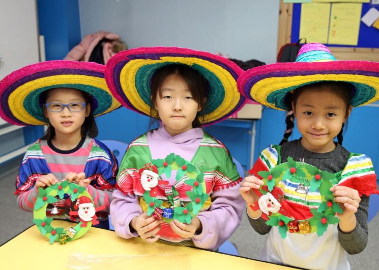 멕시코관에 참여한 초등학생들이 멕시코 의상(판초와 솜브레로)을 입고 직접 만든 작은 크리스마스 장식을 들고 기념사진을 찍고 있다.