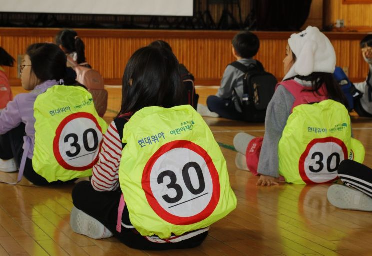 현대위아는 어린이들의 안전한 통학을 위해 교통안전 가방덮개를 배포하는 사회공헌 활동을 시행하고 있다./사진=현대위아
