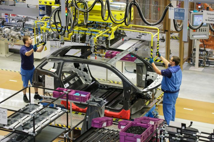 BMW 라이프치히 공장 직원들이 협동 로봇과 함께 차체 조립 작업을 하고 있다.