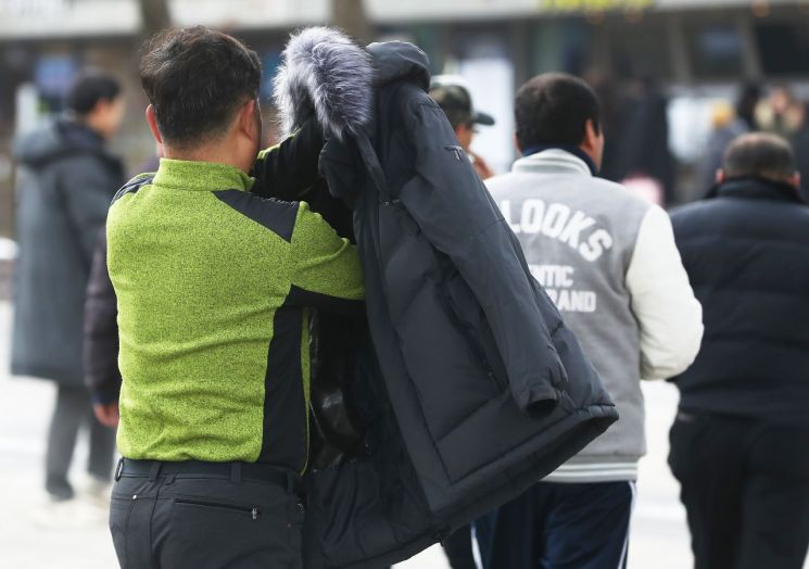 흐리고 포근한 날씨를 보인 29일 남산 산책로를 걷던 한 시민이 두꺼운 겉옷을 벗고 있다. / 사진=연합뉴스