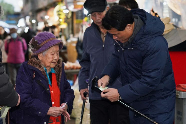 이승로 성북구청장(오른쪽 첫번째)이 시장을 찾은 어르신의 지팡이에 형광테이프를 붙여드리고 있다.