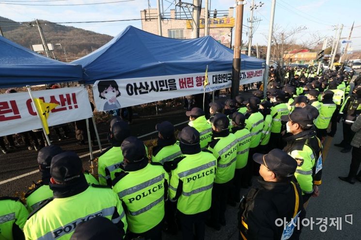 30일 우한 교민의 격리수용 장소로 결정된 충남 아산 경찰인재개발원 인근 도로에서 경찰이 주민들이 가져다 놓은 농기계를 도로 밖으로 옮긴 뒤 경계 근무를 서고 있다. 경찰 앞에 '아산 시민을 버린 행정, 대한민국 정부가 버린 아산' 글귀가 적힌 천막이 설치돼 있다. /문호남 기자 munonam@