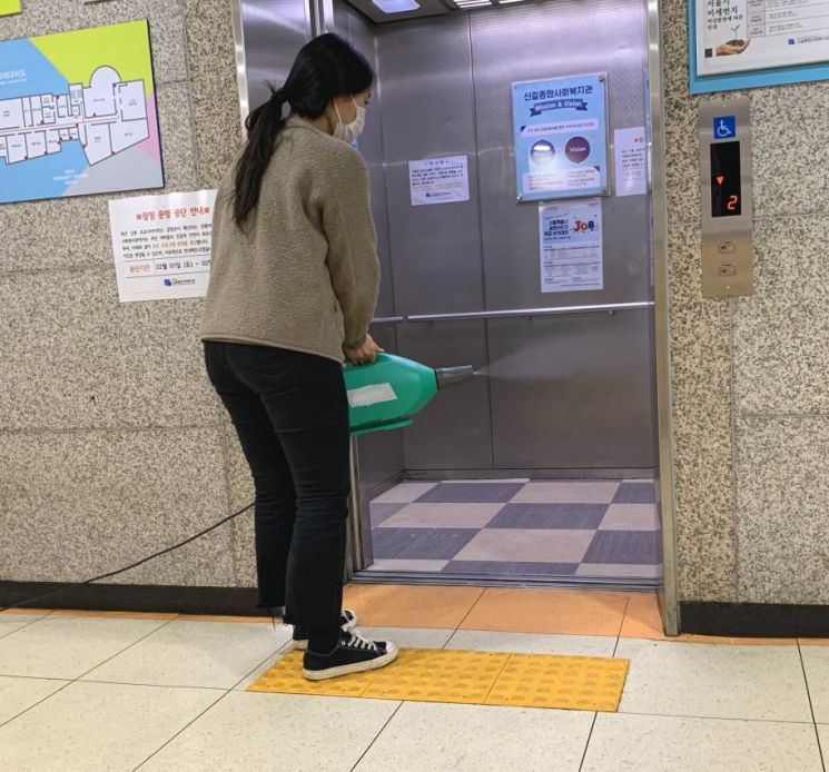 구 방역 담당자가 방역 소독기로 복지시설 엘리베이터를 소독하고 있다.