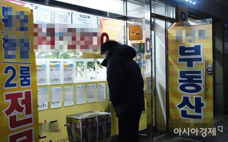 25일 서울 성동구의 한 공인중개업소 앞에서 한 시민이 마스크를 낀 채 매물표를 보고 있다. 업소에는 '마스크를 착용하고 상담한다'는 안내문이 붙어 있다.