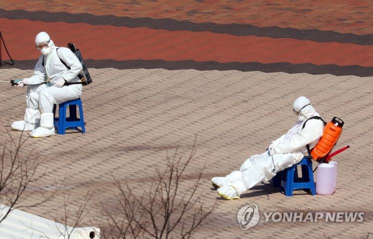 지난 6일 오후 대구시 수성구 노변동 대구스타디움에 마련된 119구급차 집결지에서 구급차 방역 임무를 맡은 대원이 소독약품통을 등에 멘 채로 잠시 휴식을 취하고 있다. [이미지출처=연합뉴스]